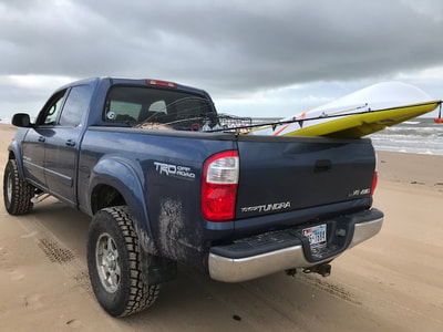 2004 Toyota Tundra Blue Truck on Beach with kayak in truck bed.