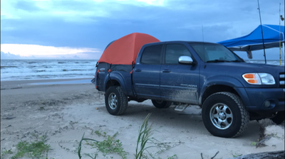 Blue 1st gen Tundra on the beach with truck bed tent and Rightline Gear truck bed tent.